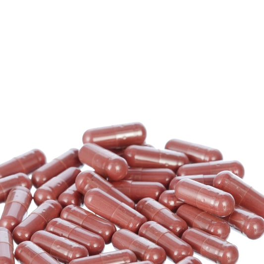 a pile of red capsules or pills scattered on a white background.