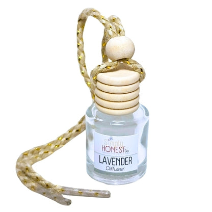 A clear glass bottle with a wooden lid and a wooden bead hanging from it, containing a clear liquid that appears to be a lavender-scented diffuser oil.