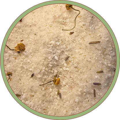 A close-up view of a white, granular substance, possibly salt or sugar, with small yellow flowers or dried petals scattered throughout.